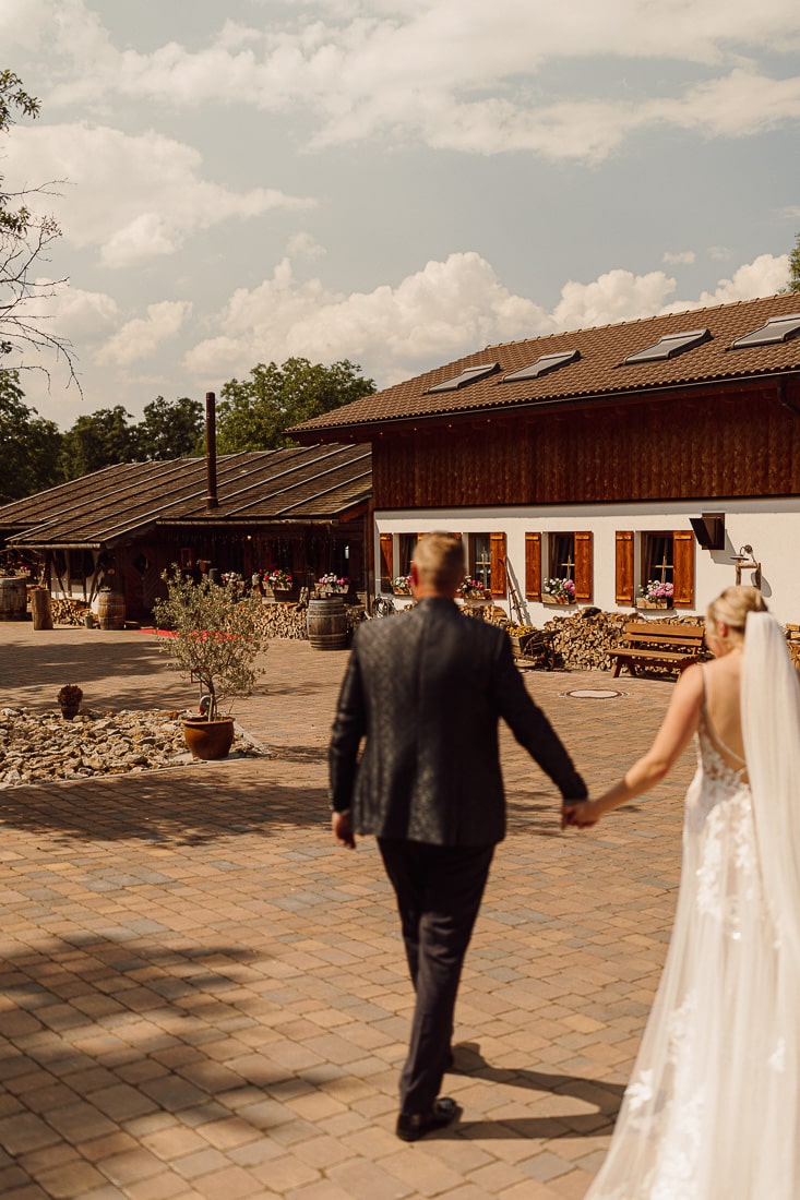 Brautpaar Hand in Hand auf dem Weg zum Hof des Landguts