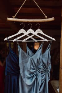 Drei satinblaue Kleider h&auml;ngen an einem rustikalen Ast &ndash; perfekt f&uuml;r ein Fotoshooting an einer Eventlocation in Frankfurt.